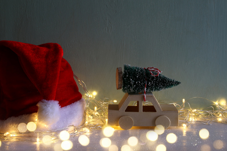 Low key image of wooden car carrying a christmas tree next santa claus hatの写真素材