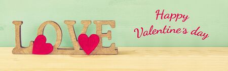 Valentines day background. Word LOVE from wooden letters and red hearts on old tableの写真素材