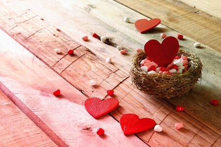 Valentines day background. Couple of red hearts in the bird nest on wooden table. Retro filtered and tonedの写真素材
