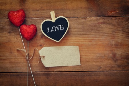 Valentines day background. Couple of red glitter hearts and empty tag for copy space on wooden background. Flat lay compositionの写真素材