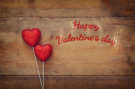 Valentines day background. Couple of red glitter hearts on wooden background. Flat lay composition