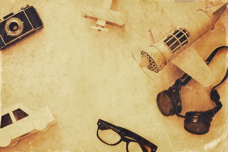 Top view of vintage toy plane, old photo camera, pilot glasses and wooden car. Sepia filtered and toned imageの写真素材