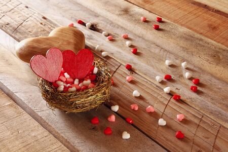 Valentines day background. Couple of red hearts in the bird nest on wooden tableの写真素材