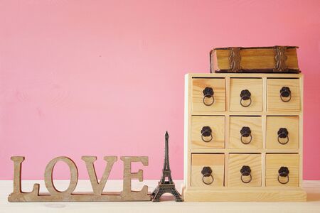 Image of natural wooden antique chest with drawers next to old book and eiffel tower and metal handlesの写真素材
