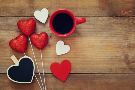 Valentines day background. Red hearts and cup of coffee on wooden background. Flat lay compositionの写真素材