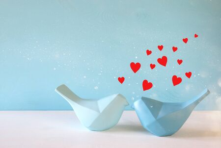 Couple of Lovebirds on wooden table in front of blue pastel backgroundの写真素材
