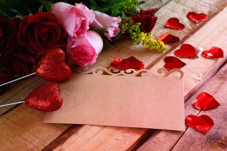 Valentines day background. Beautiful bouquet of roses next to empty letter on wooden tableの写真素材