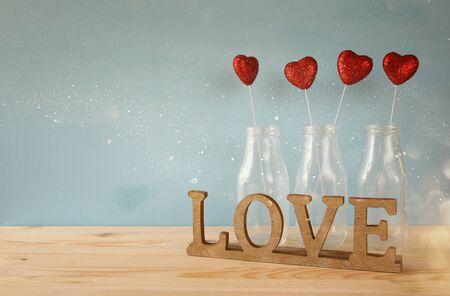 Valentines day background. Glitter hearts in the glass vases on wooden tableの写真素材