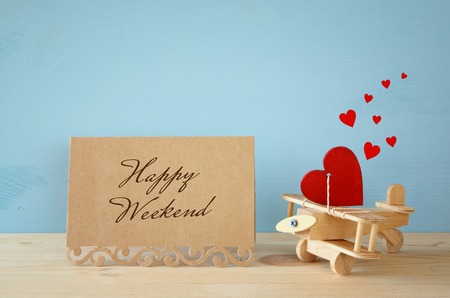 Wooden plane with heart next to greeting card on the tableの写真素材