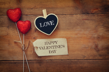 Valentines day background. Couple of red glitter hearts and tag on wooden background. Flat lay compositionの写真素材