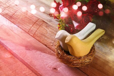 Valentines day background. Couple of loving birds in the nest on wooden table. Filtered and toned with glitter overlayの写真素材