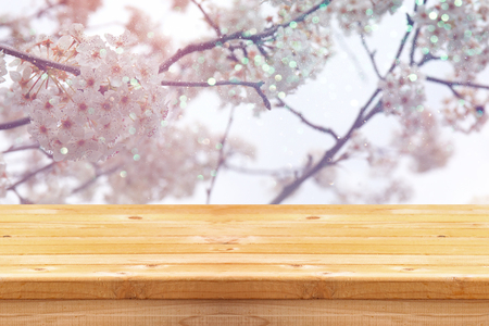 wooden rustic table in front of spring white cherry blossoms tree. vintage filtered image. product display and picnic conceptの写真素材