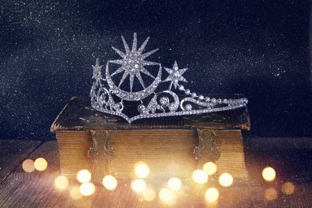 low key image of beautiful diamond queen crown on old book. vintage filtered with glitter overlay....