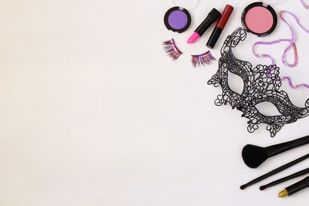 Top view image of carnival makeup and lace venetian mask on white wooden backgroundの写真素材
