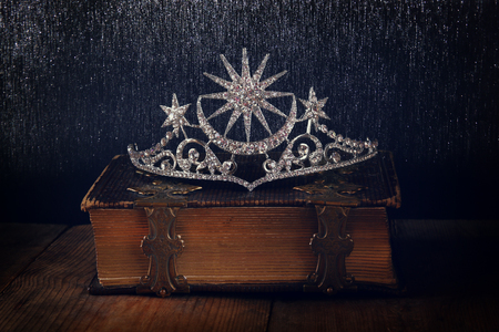 low key image of beautiful diamond queen crown on old book. vintage filtered with glitter overlay. selective focus. medieval period conceptの写真素材