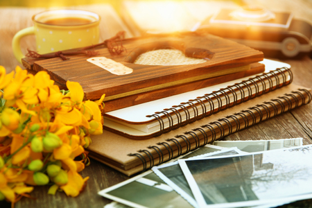 old book, vintage photo camera next to field flowers on wooden table outdoors at afternoon. selective focusの写真素材