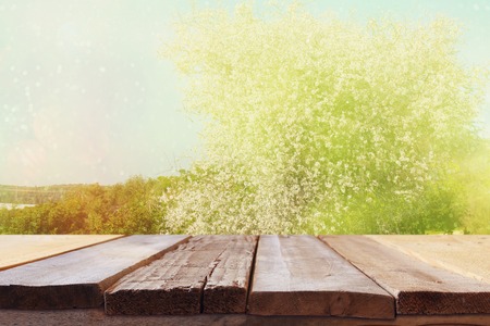 wooden rustic table in front of spring white cherry blossoms tree. vintage filtered image. product display and picnic conceptの写真素材