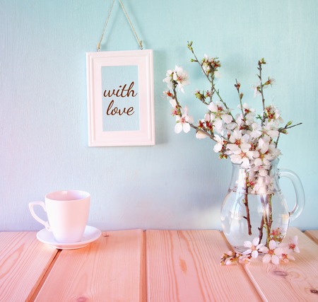 cup of coffee next to spring white flowers on wooden tableの写真素材