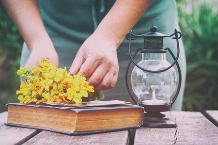 Vintage oriental lantern next to book and young girl outdoors in the garden at sunset light