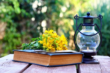 Vintage oriental lantern next to book over wooden table outdoors in the garden at sunset lightの写真素材