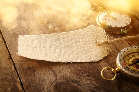 Image of antique pocket clock, compass and empty canvas tag on wooden tableの写真素材