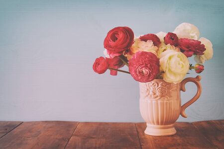 Bouquet of pink and white rosses in the vintage white vase on wooden tableの写真素材