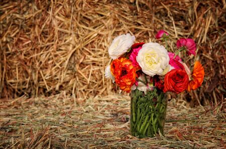 Image of beautiful spring bouquet of flowers on dry wheat haystackの写真素材