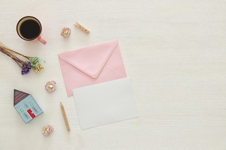 vintage mockup with flowers, cup of coffee and blank letter on white wooden backgroundの写真素材
