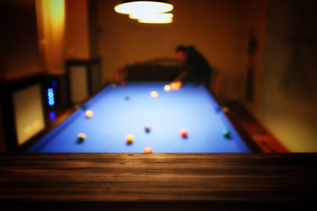 Image of wooden table in front of abstract blurred snooker player background. Montage and product display/presentationの写真素材