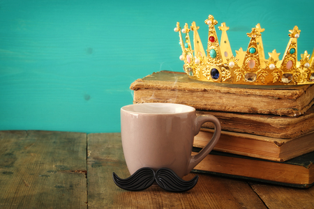 Cup of coffee with mustache and king crown on wooden table. Father's day conceptの写真素材