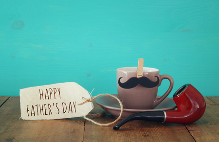 Cup of coffee with mustache and smoking pipe on wooden table. Father's day conceptの写真素材