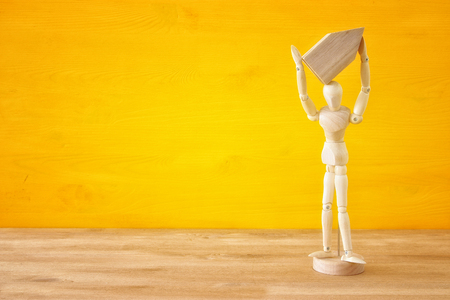 Wooden dummy holding house model. Real estate concept.の写真素材