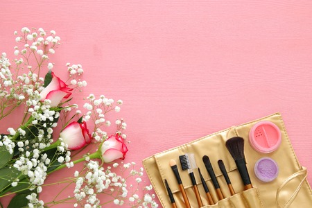 Top view of beautiful roses next to makeup on wooden background.の写真素材