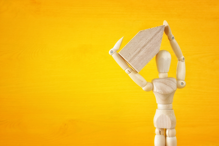 Wooden dummy holding house model. Real estate concept.の写真素材