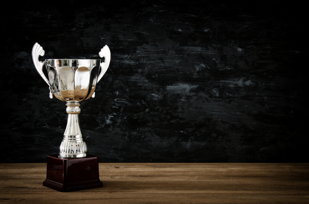 low key image of trophy over wooden table and dark background.の写真素材