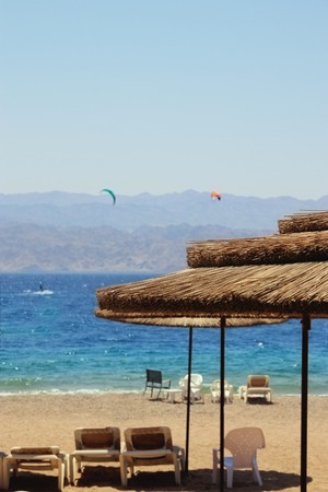 Photo of tropical sea and beach chairs under umbrellas. Summer travel and vacation concept
