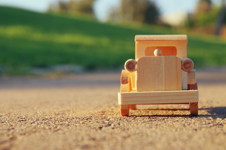 old wooden toy car on the road outdoors in the park at sunset. nostalgia and simplicity conceptの写真素材