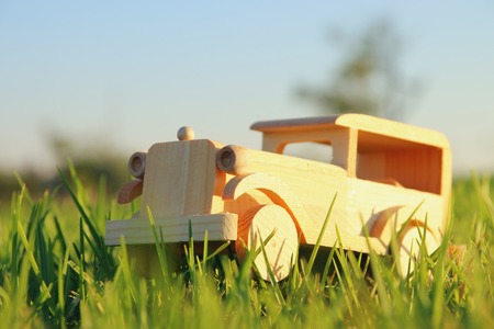 old wooden toy car in the grass outdoors in the park at sunset. nostalgia and simplicity conceptの写真素材