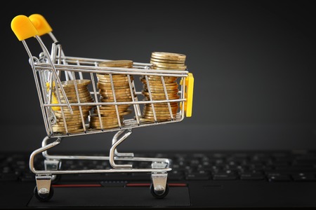 stack of coins in a trolley on a laptop keyboard. make money or shopping online, electronic commerce conceptの写真素材