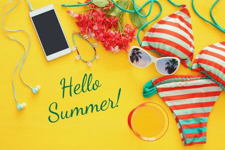 Top view of fashion female swimsuit bikini on yellow wooden background. Summer beach vacation conceptの写真素材