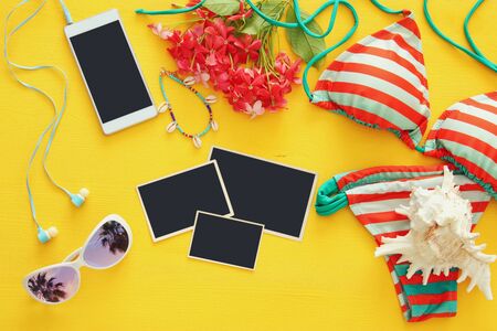 Top view of fashion female swimsuit bikini on yellow wooden background. Summer beach vacation...