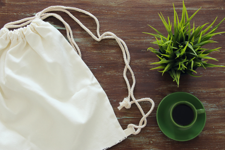 Top view image of fabric shopping bag and cup of coffee on wooden background.の写真素材