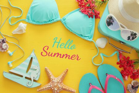 Top view of fashion female swimsuit bikini on yellow wooden background. Summer beach vacation conceptの写真素材