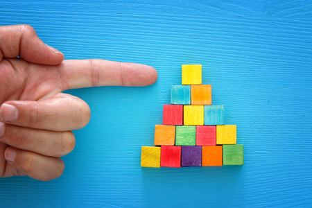 top view image of a male hand pointing to the top of wood blocks pyramid , human resources and management concept.の写真素材