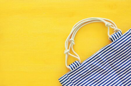 Top view of nautical summer/beach bag on yellow wooden background.の写真素材