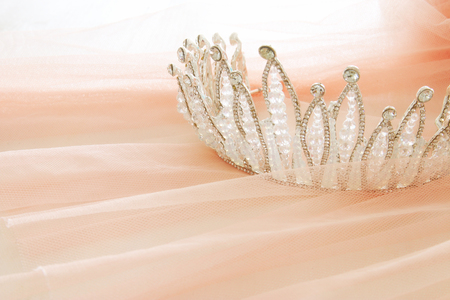 Vintage tulle pink chiffon dress and diamond tiara on wooden white table. Wedding and girl's party concept.の写真素材