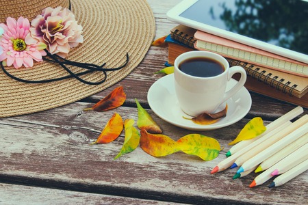 Digital tablet, books, colorfull pencils and cup of coffee on old wooden table outdoor in the parkの写真素材
