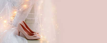 Beautiful white wedding dress and veil on chair with gold garland lights.の写真素材