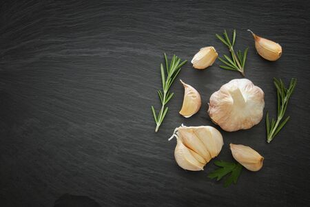Image of garlic and rosemary on slate stone plate.