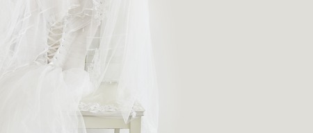 Beautiful white wedding dress and veil on chair.
